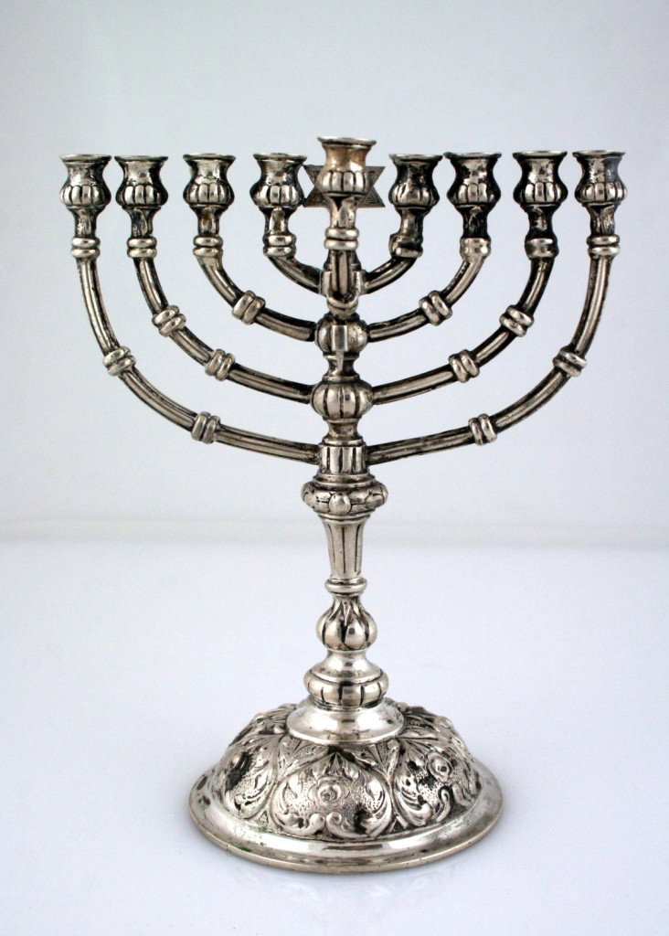 A SILVER TEMPLE STYLE CHANUKAH MENORAH. Vienna, c. : A SILVER TEMPLE STYLE CHANUKAH MENORAH. Vienna, c. 1920. Heavily chased bottom. With removable servant lamp. 7.9" tall.