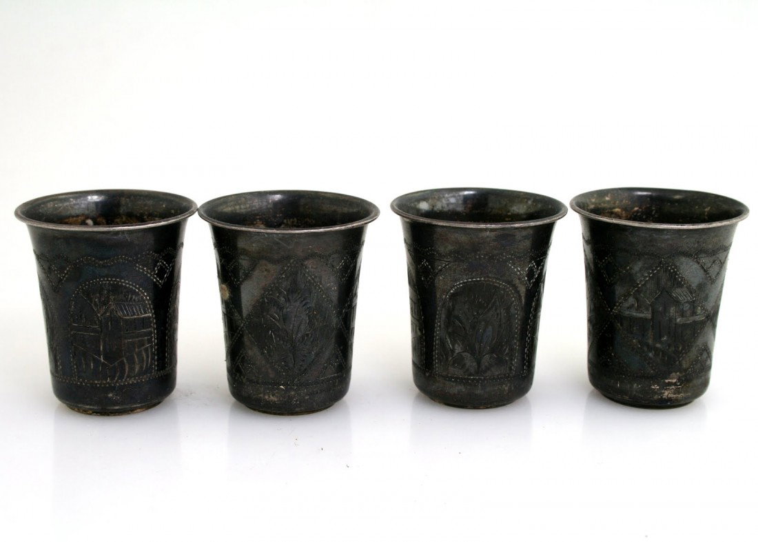 A SET OF FOUR SILVER KIDDUSH BEAKERS. Russia, 1890: A SET OF FOUR SILVER KIDDUSH BEAKERS. Russia, c. 1890. Each matching. Decorated with engraved scenes of houses and flowers. 1.8” tall each. Marked.