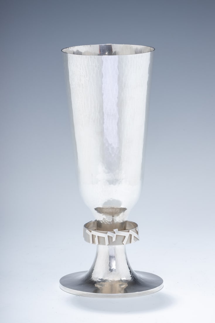 A RARE MONUMENTAL STERLING SILVER KIDDUSH CUP BY DAVID HEINZ GUMBEL. Israel, c. 1980. On a round: A RARE MONUMENTAL STERLING SILVER KIDDUSH CUP BY DAVID HEINZ GUMBEL. Israel, c. 1980. On a round base. With â€œELIJAH THE PROPHET” spelled out in Hebrew along the stem that attaches to a