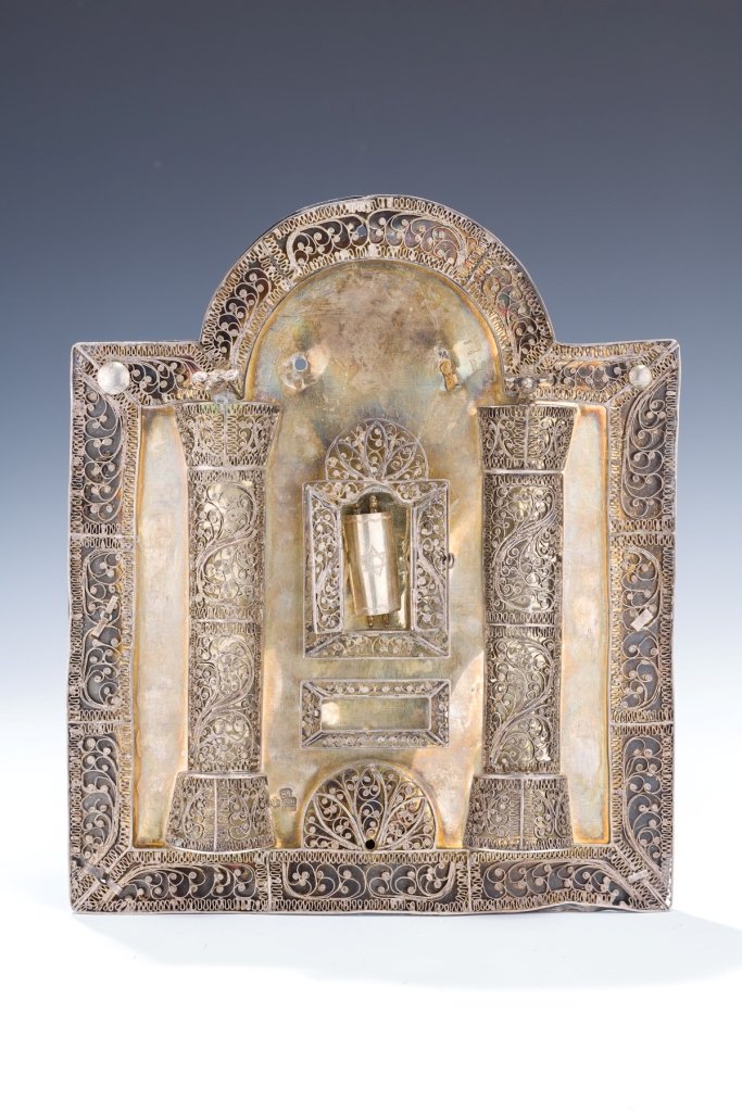 A SILVER TORAH SHIELD: A SILVER TORAH SHIELD. Russian, 1887. With borders, pillars and central ark made of filigree. Center crown now missing. 10” tall.