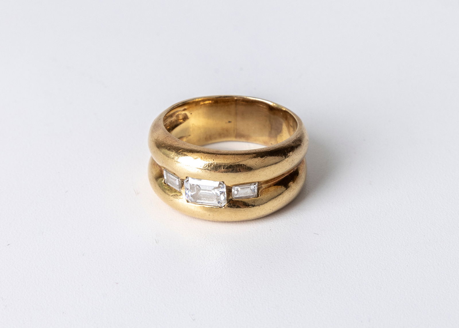 A LADIES 18K YELLOW GOLD THREE STONE EMERALD CUT DIAMOND BAND. The center diamond measures 6.10 mm i (1 of 5)