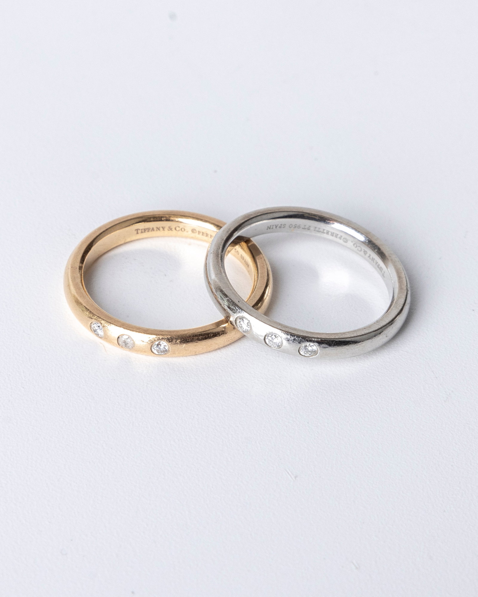 ONE PLATINUM AND ONE 18K YELLOW GOLD TIFFANY AND COMPANY THREE STONE FULL CUT DIAMOND BAND. Each tot: ONE PLATINUM AND ONE 18K YELLOW GOLD TIFFANY AND COMPANY THREE STONE FULL CUT DIAMOND BAND. Each totalling .15 carats. Average clarity grade is VS-1 and color grade of G. Both are sizes 6.5. The 18K b