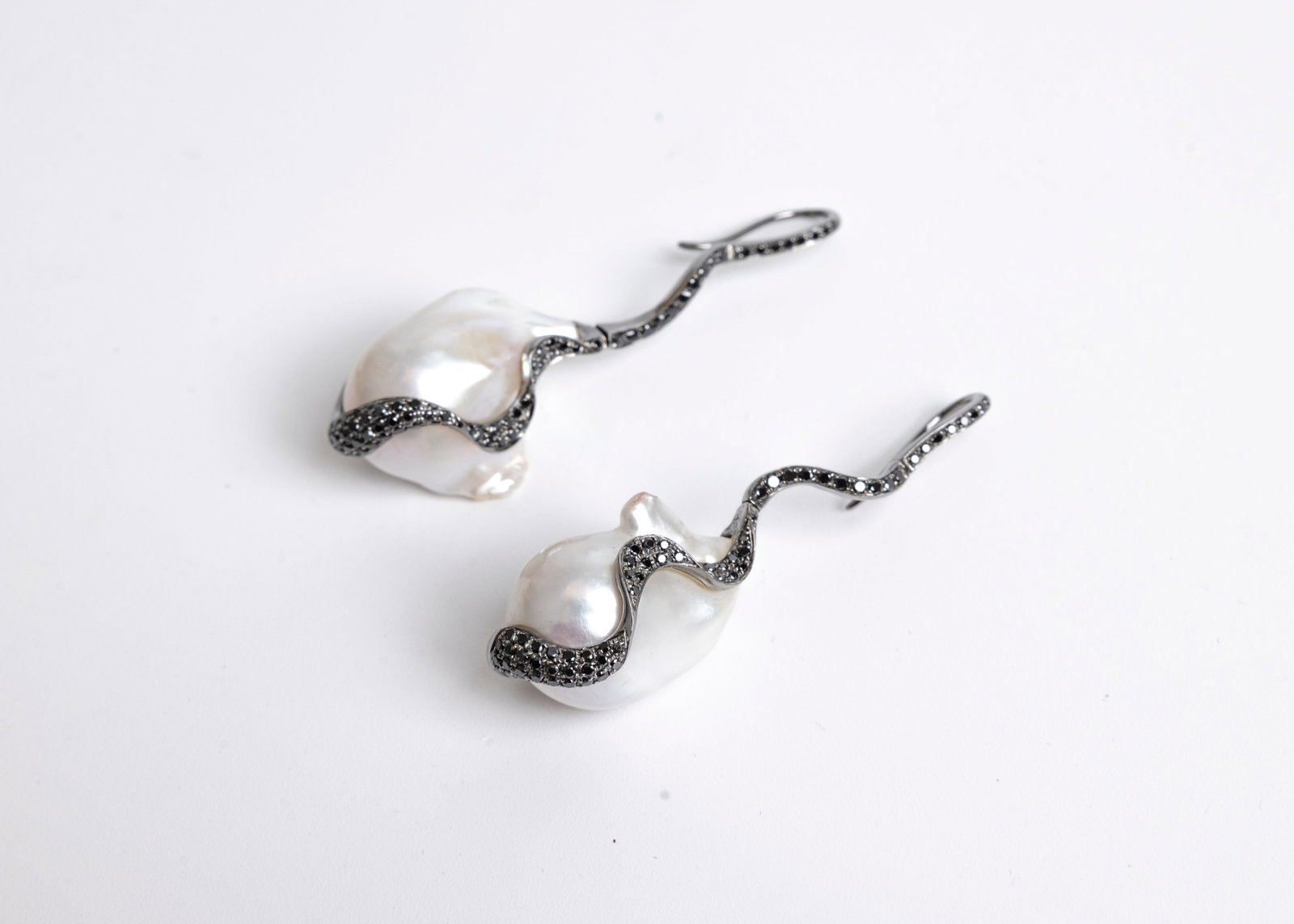 A PAIR OF OXIDIZED 18K WHITE GOLD BAROQUE CULTURED PEARLS. Accented with 134 black diamonds. The pea: A PAIR OF OXIDIZED 18K WHITE GOLD BAROQUE CULTURED PEARLS. Accented with 134 black diamonds. The pearls measure 23.0 mm x 20.28 mm and 23.00 mm x 14.5mm. The black diamonds range from 0.005 - 0.010 ca