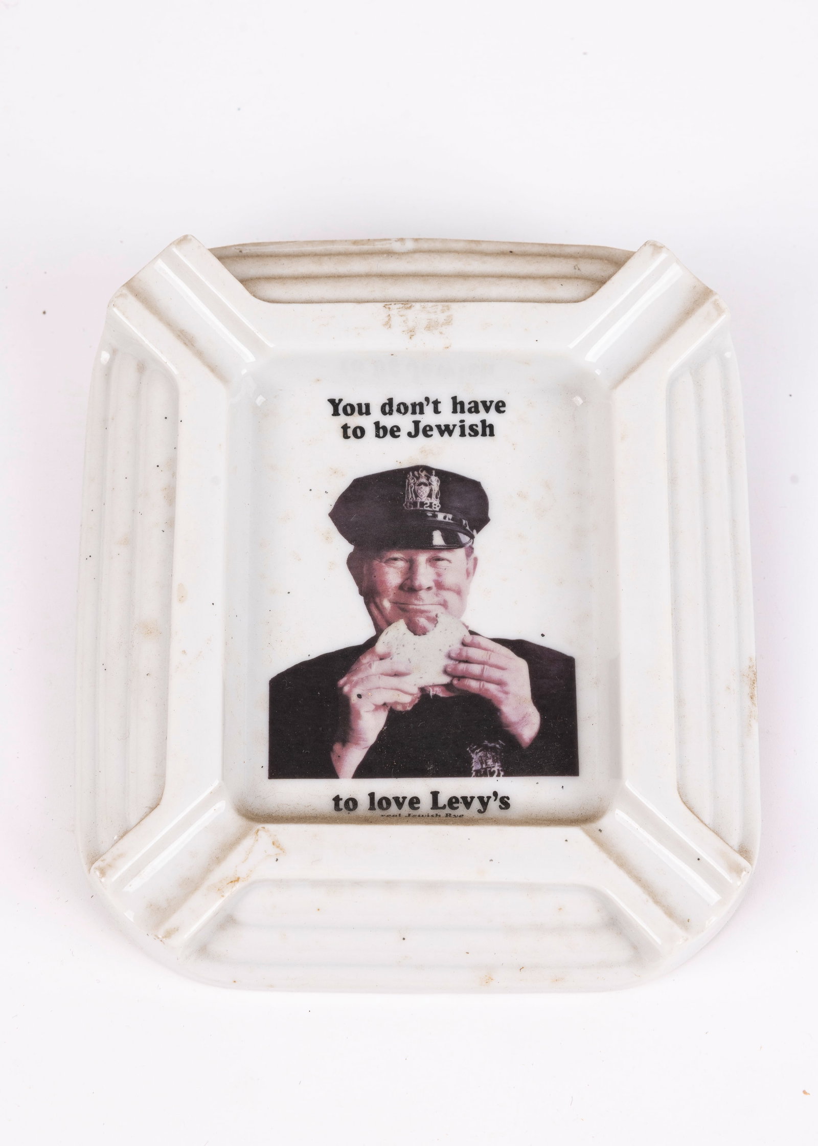 A LEVY’S RYE ASHTRAY. United States, c. 1970. Decorated with an Irish NYC policeman eating (1 of 1)
