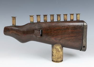 A TRENCH ART HANUKKAH MENORAH. Israel, Mid-century. Made from a rifle butt and spent shells.11.5