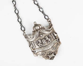 A SILVER WINE BOTTLE LABEL. Germany, c. 1900. Cartouche form. Engraved with a partial blessing over