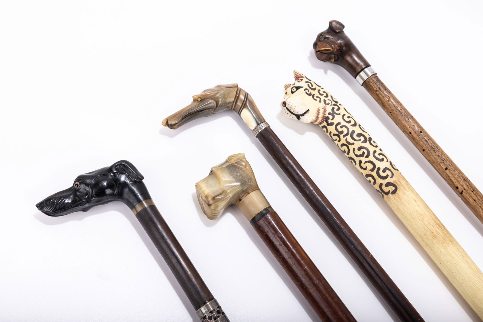 A GROUP OF FIVE ANIMAL SHAPED HANDLED DRESS CANES/WALKING STICKS. Continental. Made from a variety: A GROUP OF FIVE ANIMAL SHAPED HANDLED DRESS CANES/WALKING STICKS. Continental. Made from a variety of mediums including antler and wood. Includes four dogs and a leopard.