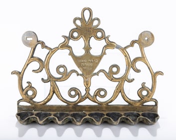 RARE AND EARLY BRASS HANUKKAH LAMP. Greece, 19th century. The backplate with scrolling designs.
