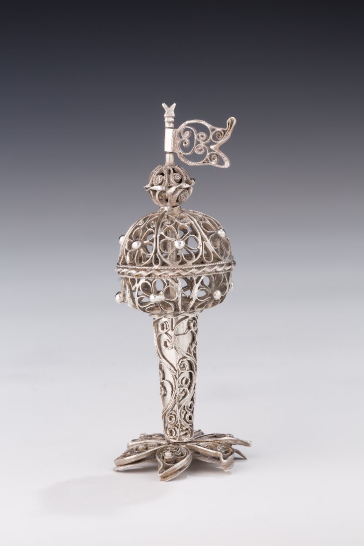 A SILVER FILIGREE SPICE CONTAINER. Ukraine, c. 1800. On: A SILVER FILIGREE SPICE CONTAINER. Ukraine, c. 1800. On starfish shaped base. With filigree and solid stem that connects to upper spice chamber. Topped by a filigree flag. 4” tall. Estimate $1,500 �