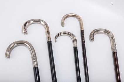 A GROUP OF FIVE SILVER HANDLED DRESS CANES. Each with a crook handle and chased and embossed overlay
