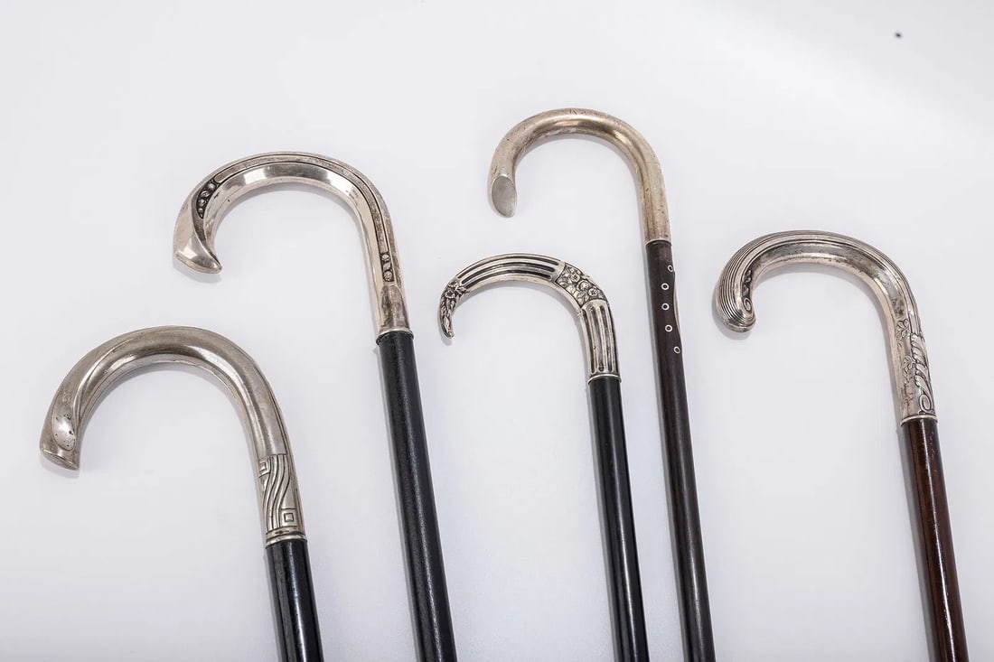 A GROUP OF FIVE SILVER HANDLED DRESS CANES. Each with a crook handle and chased and embossed overlay (1 of 5)
