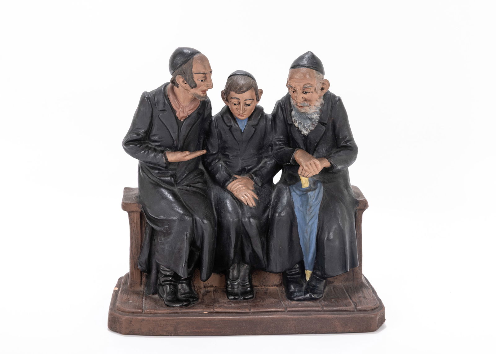 100. A FIGURINE OF A CHASSIDIC GRANDFATHER, FATHER AND YOUNG MAN ONE BENCH. Czechoslovakia, c. 1920.: 100. A FIGURINE OF A CHASSIDIC GRANDFATHER, FATHER AND YOUNG MAN ONE BENCH. Czechoslovakia, c. 1920. In discussion on a wooden bench. A small chip is evident on the floor. 8.4" wide.