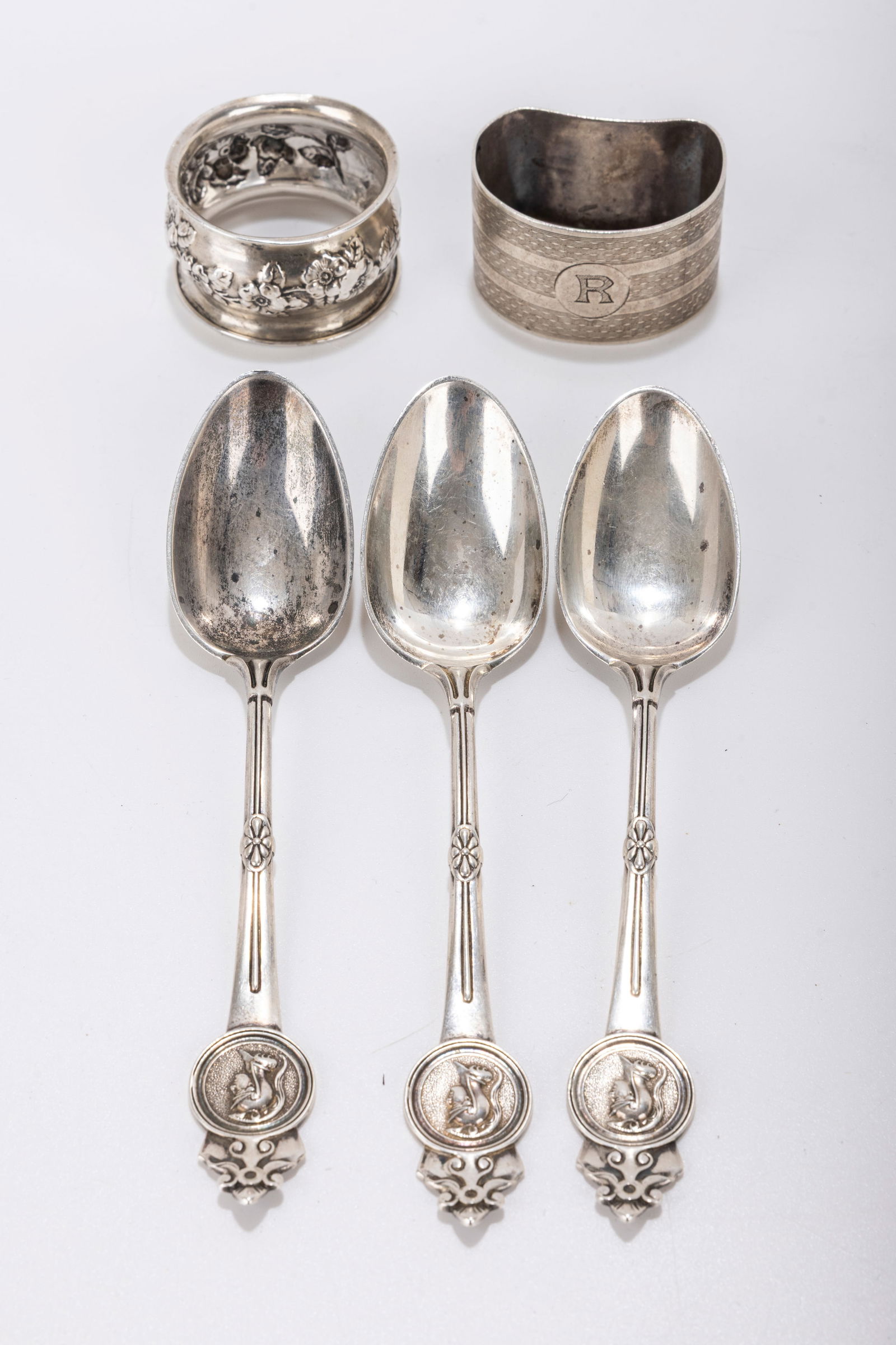 194. THREE ANTIQUE STERLING SILVER MEDALLION SPOONS AND TWO NAPKIN RINGS. The spoons by Gorham are (1 of 1)