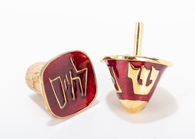 208. A DREIDEL AND A ENAMEL AND BRASS WINE STOPPER BY CHAVA WOLPERT. American, c. 1980. Gilded brass