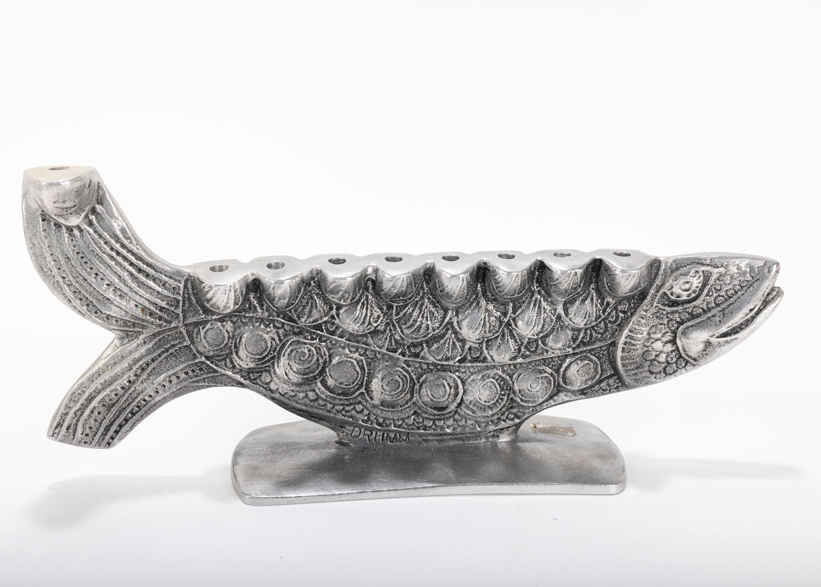 A LARGE ALUMINUM MENORAH SCULPTURE BY DON DRUMM (American, b. 1935).: A LARGE ALUMINUM MENORAH SCULPTURE BY DON DRUMM (American, b. 1935). With a fish design, on a rectangular base. Signed. 14 inches wide. Estimate $200 - 400