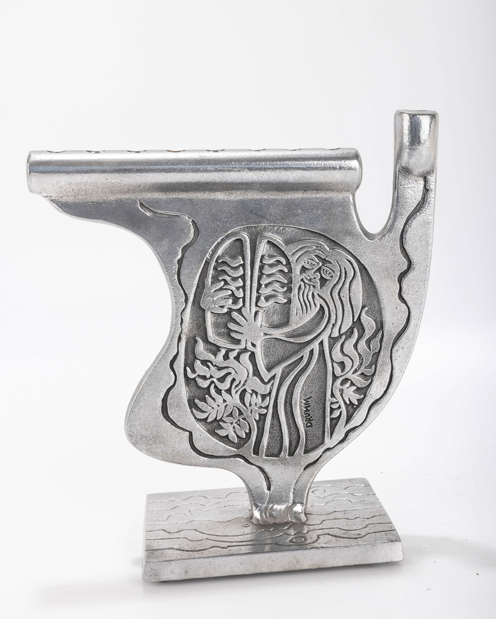 AN ALUMINUM MENORAH SCULPTURE BY DON DRUMM (American, b. 1935).: ALUMINUM MENORAH SCULPTURE BY DON DRUMM (American, b. 1935). Etched design with Moses carrying the Luchot, on a rectangular base. Signed. 8 inches wide. Estimate $200 - 400