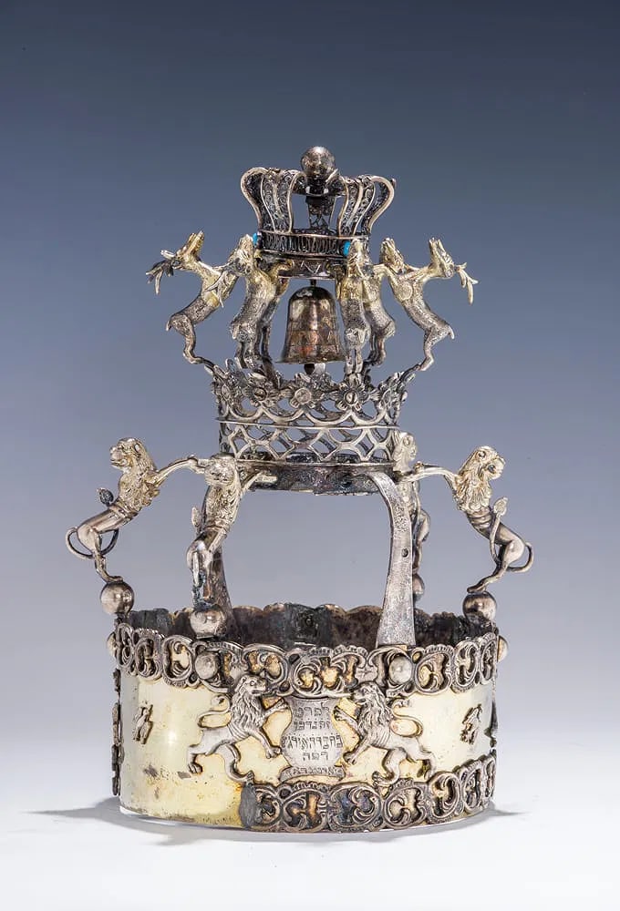 A RARE AND IMPORTANT SILVER TORAH CROWN TARNOGRAD, POLAND: Tarnograd, Poland, c. 1880. The lower part is decorated with two lions flanking a cartouche. Upper and lower borders are intertwining C-scroll designs. Further decorated with stags, birds and a duck.