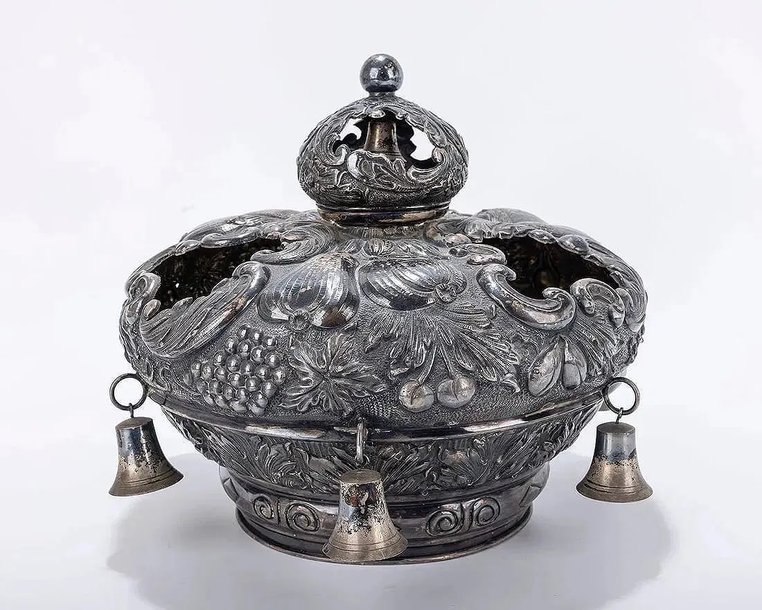 A SILVER TORAH CROWN. Hungarian, 20th century.: A SILVER TORAH CROWN. Hungarian, 20th century. Chased with fruits, scrolls and other organic designs. Fitted with six large silver bells. Inscribed with Hebrew dedication. 11" wide. Similar sold: J. G