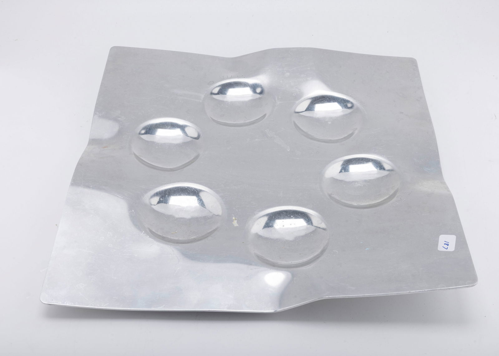 A HAND WROUGHT ALUMINUM SEDER TRAY BY LAURA COWAN MOONSCAPE: Israel, c. 1990. Square in shape. With artistic bends and the name of the Passover food engraved by each spot. Signed.