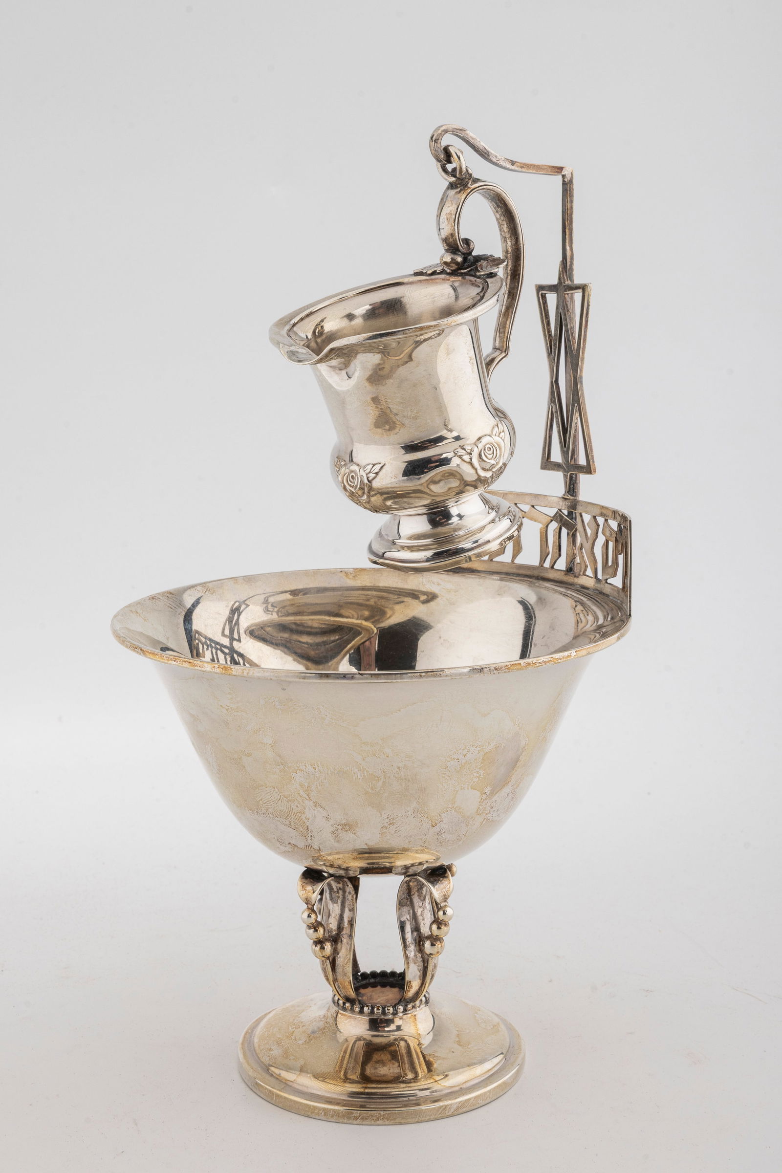 A LARGE STERLING SILVER MAYIM ACHRONIM SET. American, c. 1960: The bottom portion in Jensen-esqe design. The upper portion with Hebrew lattice work that suspends a smaller cup. 10" tall and 9.75 ozt.