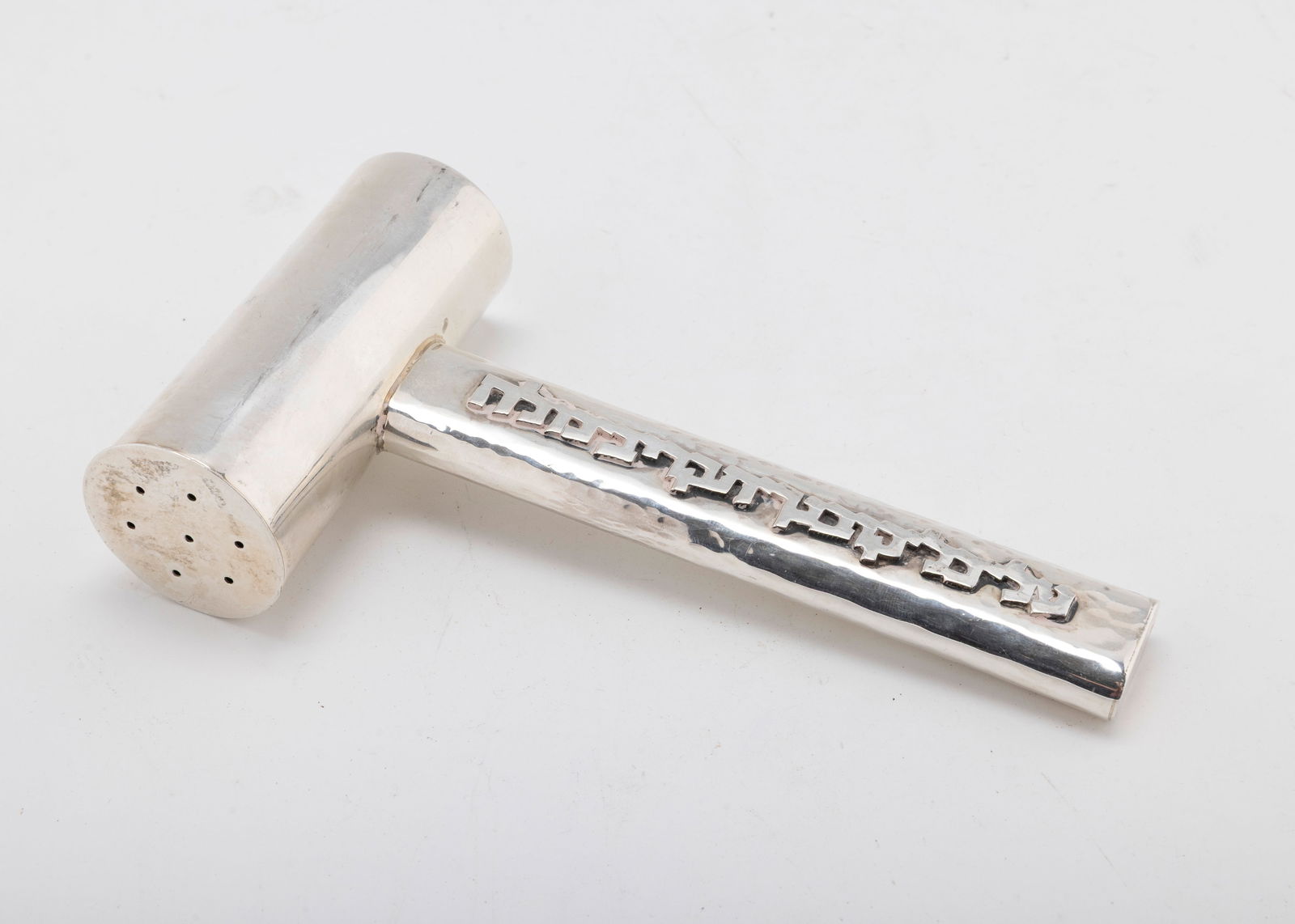 A STERLING SILVER SALT SHAKER BY BIER. Israel, c. 1990: In the form of a hammer. Hand hammered handle with applied Hebrew lettering in relation to salt. Signed Bier, 925, hand made Jerusalem. interior thin plastic lining to prevent corrosion. 6" long and 1