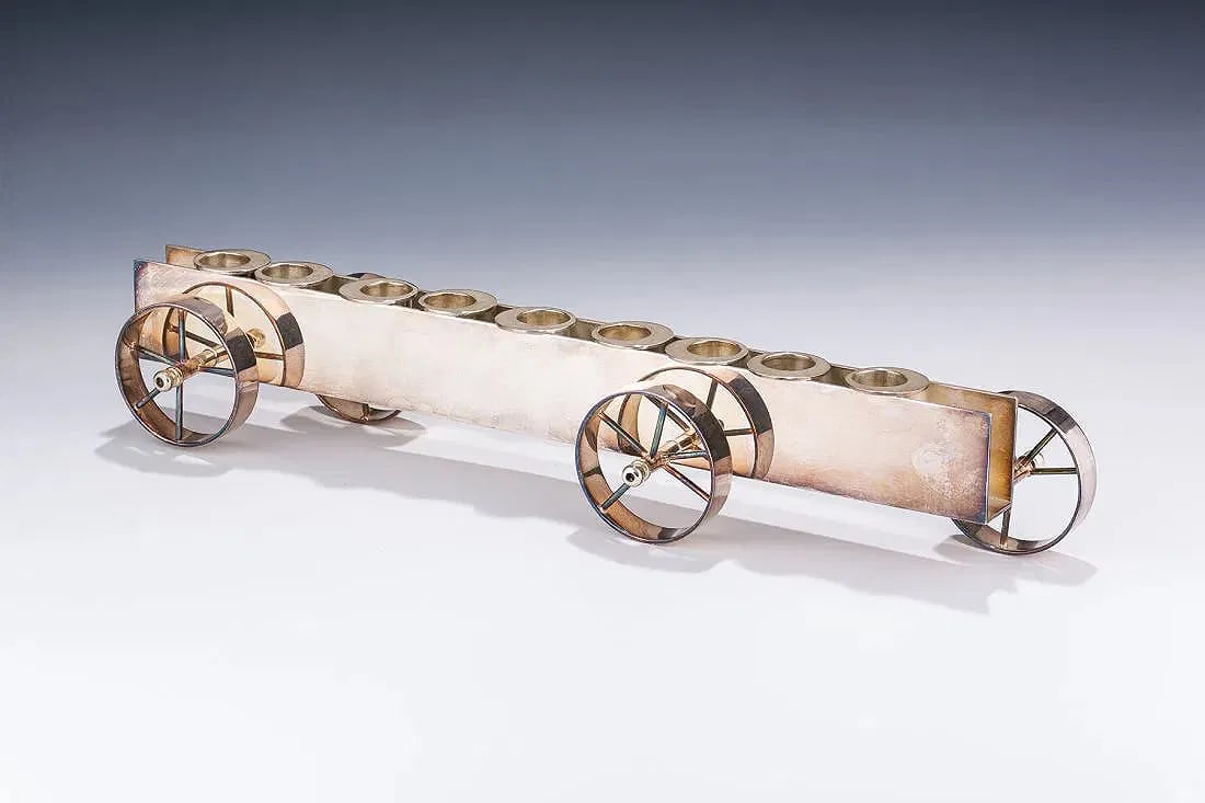 A STERLING SILVER CHANUKAH MENORAH BY PAMPOLINI. Italy.: Italy. In the shape of a wheeled cart. Marked. 15.5” long.