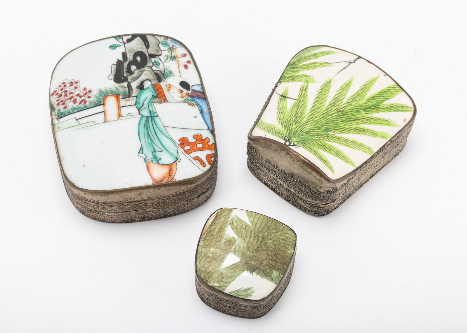 A GROUP OF THREE PORCELAIN BOXES. China, c. 1900: Most likely for pills or stamps. With silver plated metal sides. Each hand painted. Various sizes. Largest is 5.1" long
