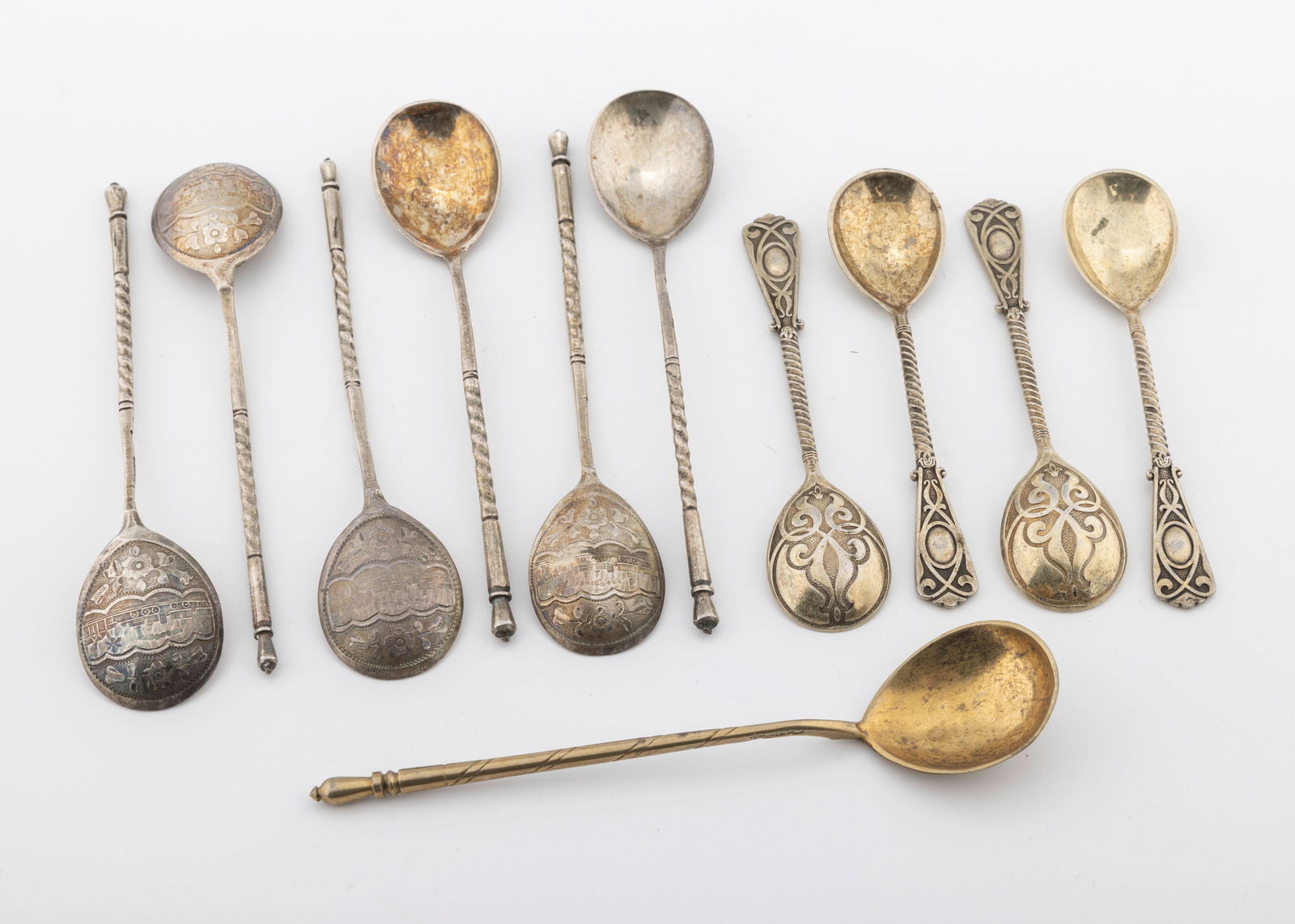 A GROUP OF SILVER APOSTLE SPOONS: Seven Russian with sharp hand engraving dated 1888 5" and5.4". and four German spoons, 4" each mared 13. Total weight of 159.2 grams