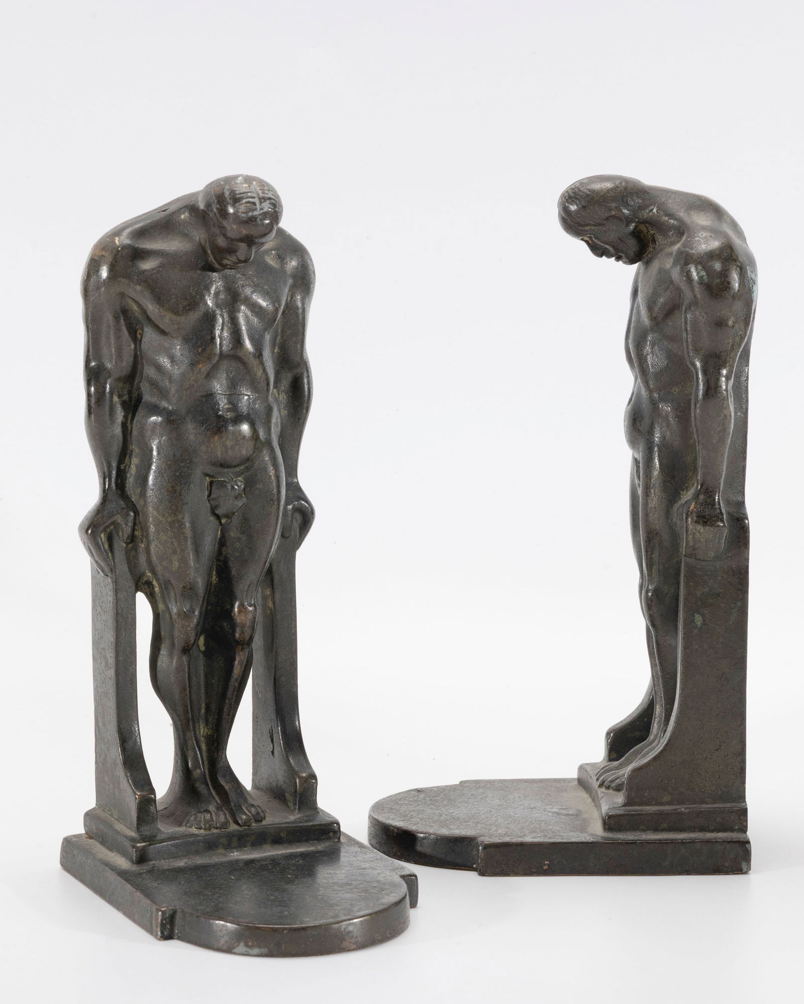 A PAIR OF BRONZE BOOKENDS IN THE MANNER OF OSCAR BACH, USA, c, 1925: Art Deco in form. Human male creature with the upper shoulders and head leaning over. 7.2" tall