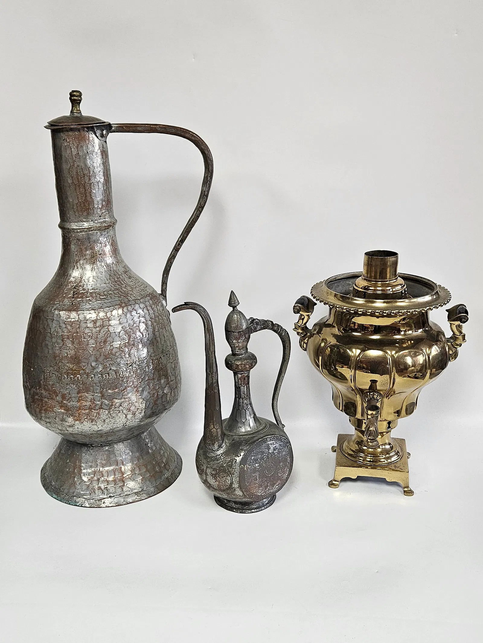 A MASSIVE HAND WROUGHT PITCHER AND AN ARABIC TEA POT: Most Likely Persian, c. 1920. The water pitcher is 25" tall and the tea pot is 15" tall. Accompanied by a partial samovar.