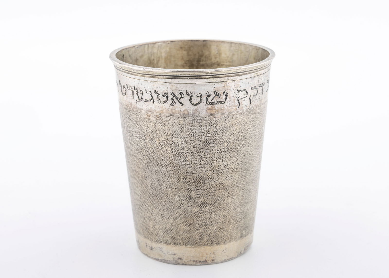 AN ANTIQUE SILVER KIDDUSH CUP. Nuremberg, 18th century: Beaker form. With hand hammered sharkskin finish. The upper part is later engraved with a Hebrew dedication to the Kehillah Kedosha of Stuttgart ated 1850. Marked. 3.5" tall and 94.4 grams