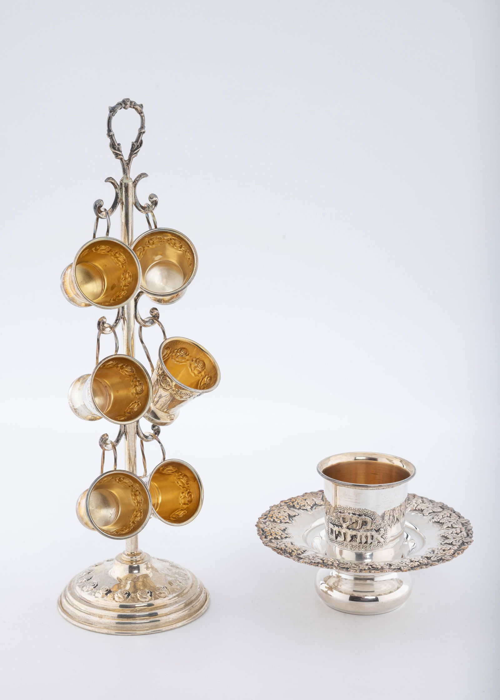 A STERLING SILVER MAYIM ACHRONIM AND BEAKER TREE. Israel, modern.: The mayim achronim (3.5" tall) embossed with grape designs. The beaker tree (11.3") with a similar motif. 280.8 grams