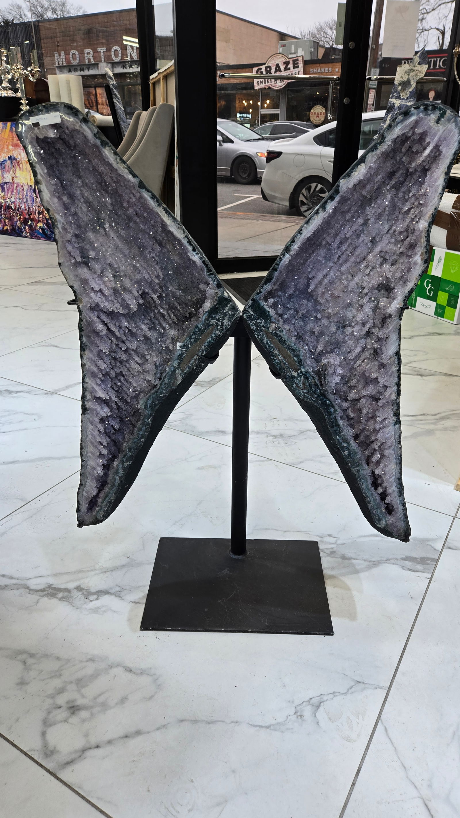 A PAIR OF MAGNIFICENT AMETHYST WINGS ON A STAND: Split in half and mounted on a black gun metal stand, these wings have a magnificent color and texture. 25" x 23" each stone. Total weight is 34.7 kilo. It is 35" tall on the stand