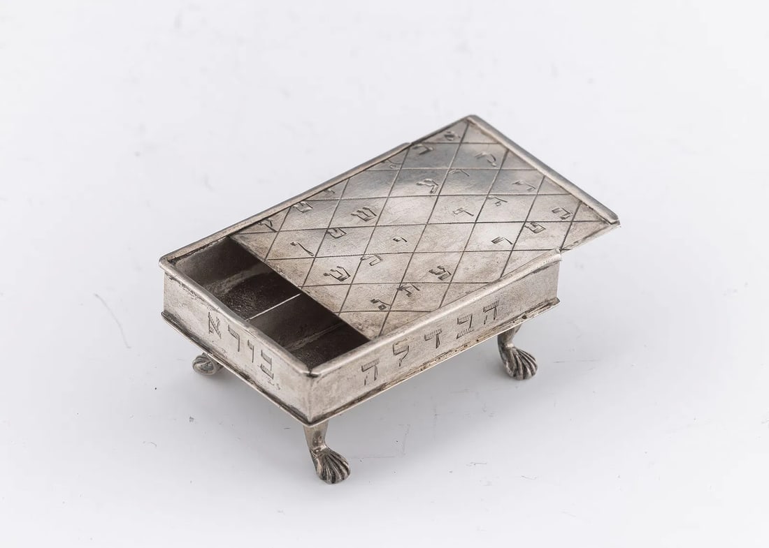 AN EARLY SILVER SPICE CONTAINER. Germany, c. 1800.: AN EARLY SILVER SPICE CONTAINER. Germany, c. 1800. On four shell feet. With a sliding top that is engraved with kabbalistic inscriptions. The base is inscribed with MM Abraham. Marked with a 12 and a