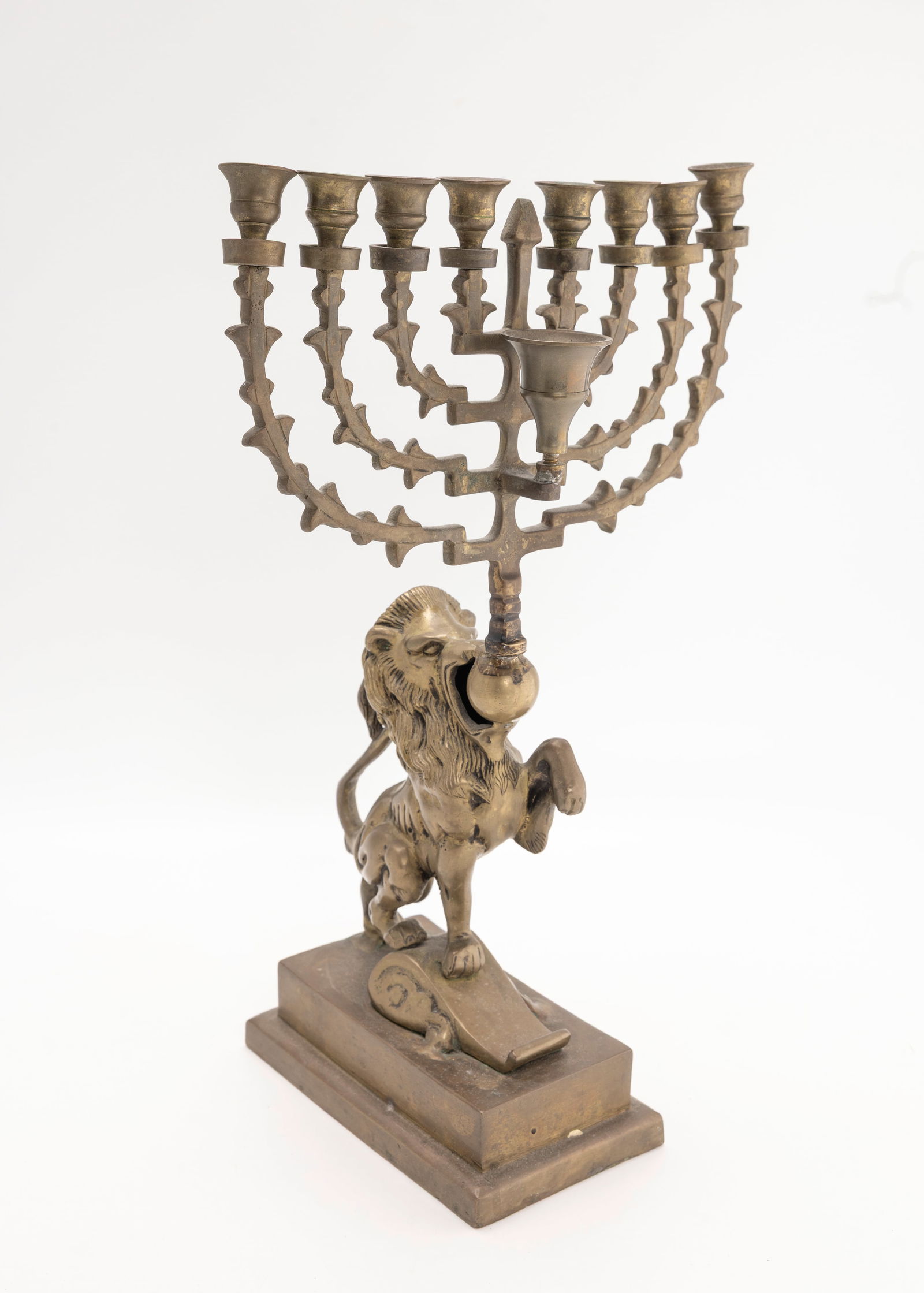 A LARGE BRASS LION FORM MENORAH.: Probably Dutch, Early 20th century. On a rectangular base with a rampant lion holding up a traditionally formed lamp. 15" tall.