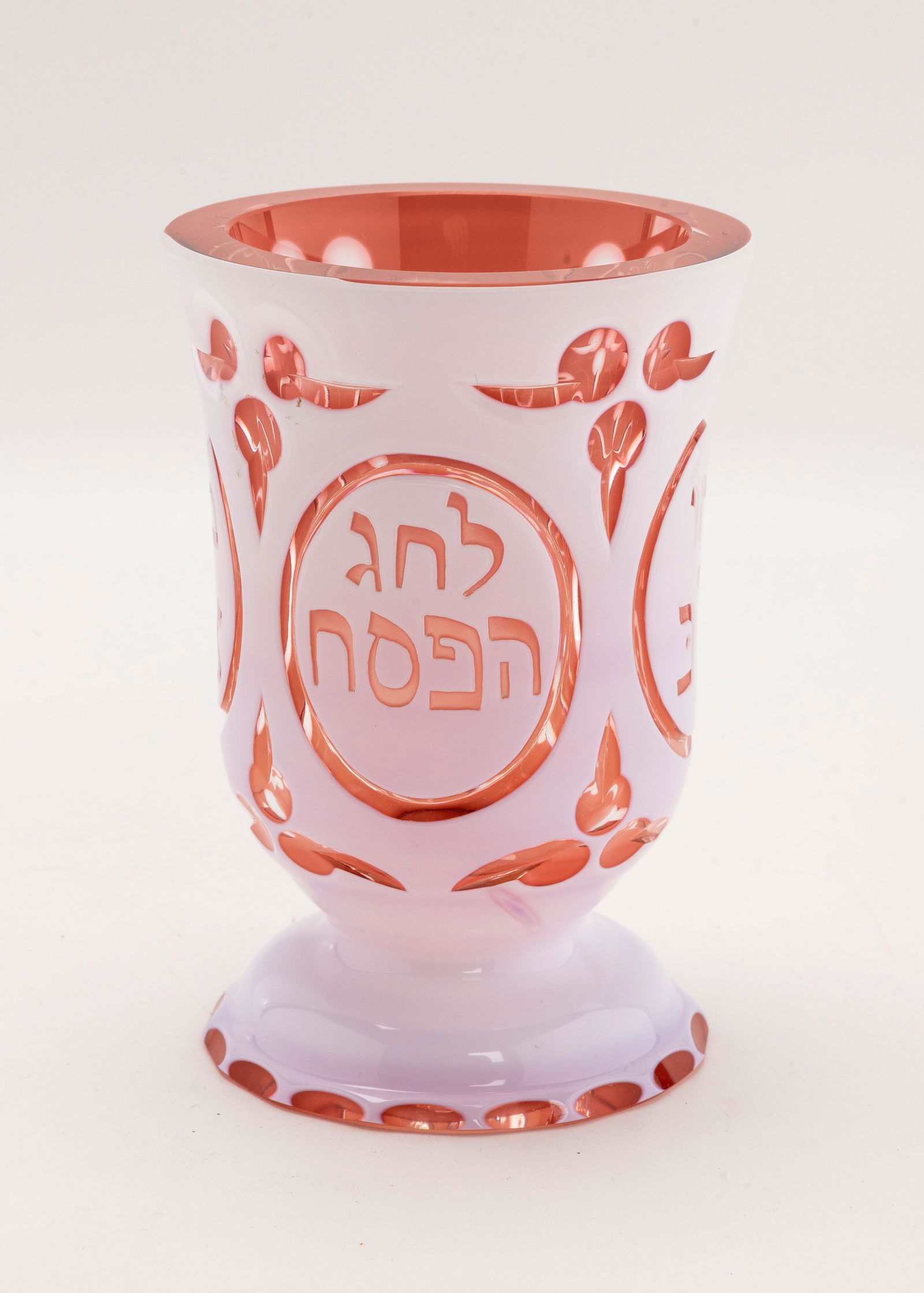 A LARGE RUBY GLASS PASSOVER GOBLET: Probably Italian, Early 20th century. With a white outer layer that covers a ruby glass body. Engraved CHAG HAPEASACH. 4.8" tall.