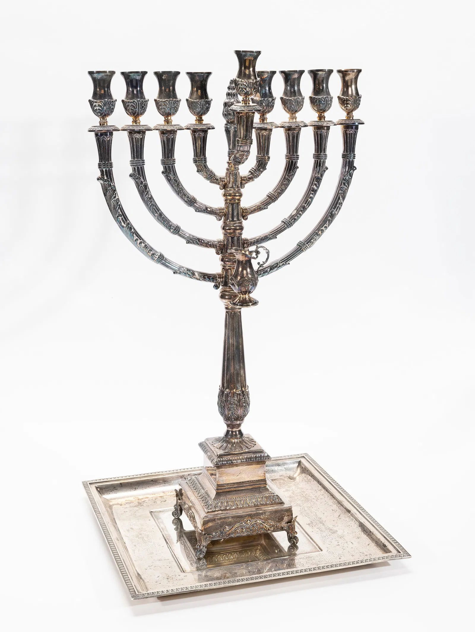 A STERLING SILVER HANUKKAH MENORAH AND UNDERTRAY. Israel.: The menorah by Hazorfim is 23" tall and 1414.8 grams. The tray is by Grand Sterling and is 13.2" x 13.2" and 1055.1 grams