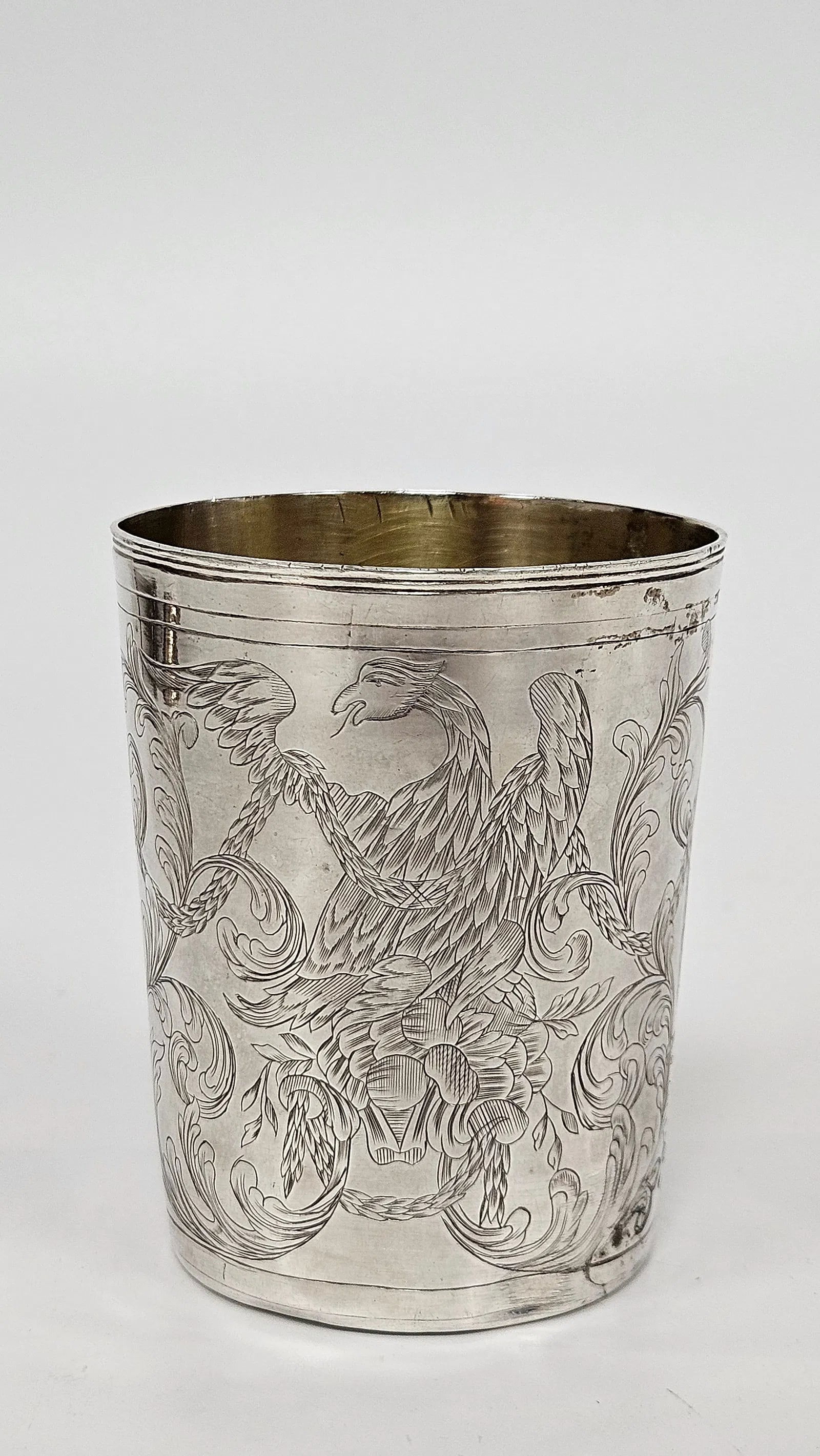 AN ANTIQUE SILVER CUP. Russia, 1786: Beaker form. Engraved with eagle scenes, organic designs, and scrolling. Marked. 3.3" tall and 2.715 ozt.