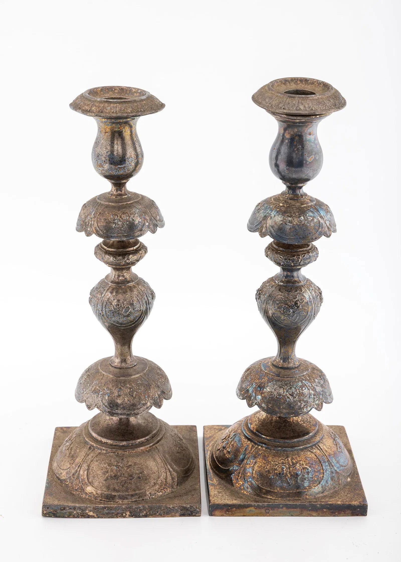 A PAIR OF BRASS SABBATH CANDLESTICKS BY NORBLIN. Warsaw, c. 1890.: Peticoat design. On square bases with floral designs and baluster shaped bodies. 12.5” tall.