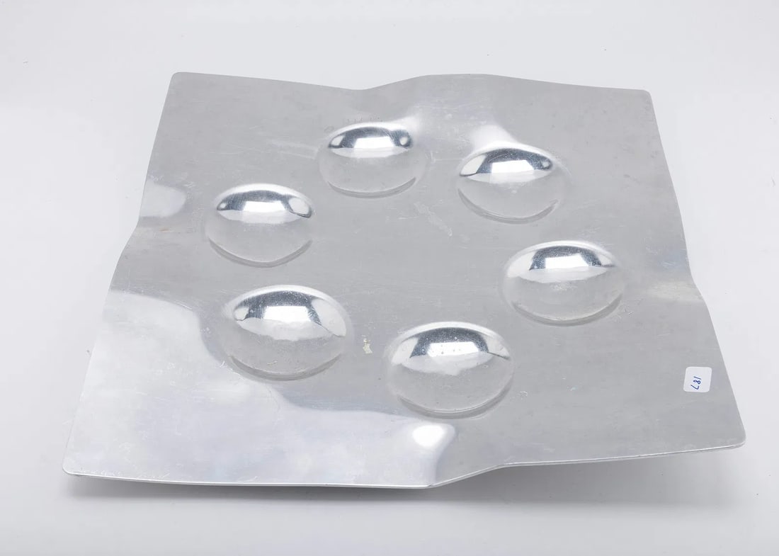 A HAND WROUGHT ALUMINUM SEDER TRAY BY LAURA COWAN MOONSCAPE: Israel, c. 1990. Square in shape. With artistic bends and the name of the Passover food engraved by each spot. Signed.