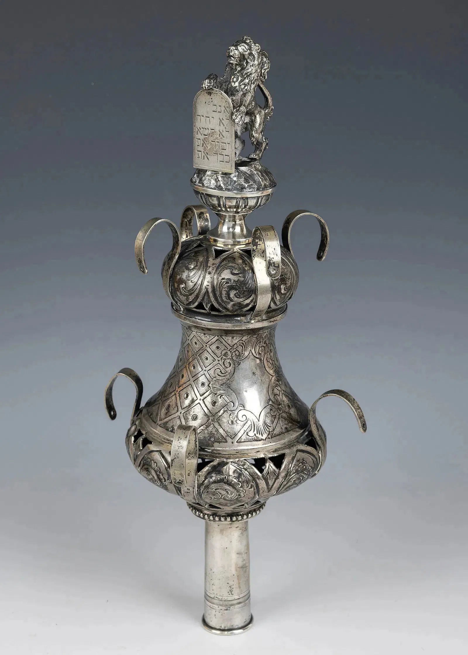 A MAGNIFICENT SILVER TORAH FINIAL WITH LION ANTIQUE JUDAICA: A SINGLE TORAH FINIAL. Germany, c. 1890. Traditional baluster shape. Fitted with a magnificent finial of a lion holding up a Decalogue. Marked. 13.2” tall.