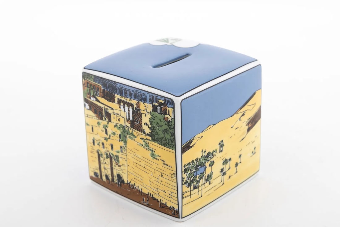 A TIFFANY PORCELAIN CHARITY BOX. American, 20th Century: Made in limited edition exclusively for the Jewish National Fund. illustrated with scenes of the holy land and the western wall. 3.3” tall