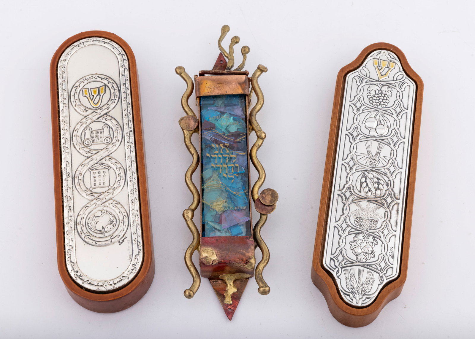 A GROUP OF THREE MEZUZAH CASES UNUSED: Composed of wood and white metal decorated with the seven species. 6.2" tall each. Made by the Genesis company in Israel.