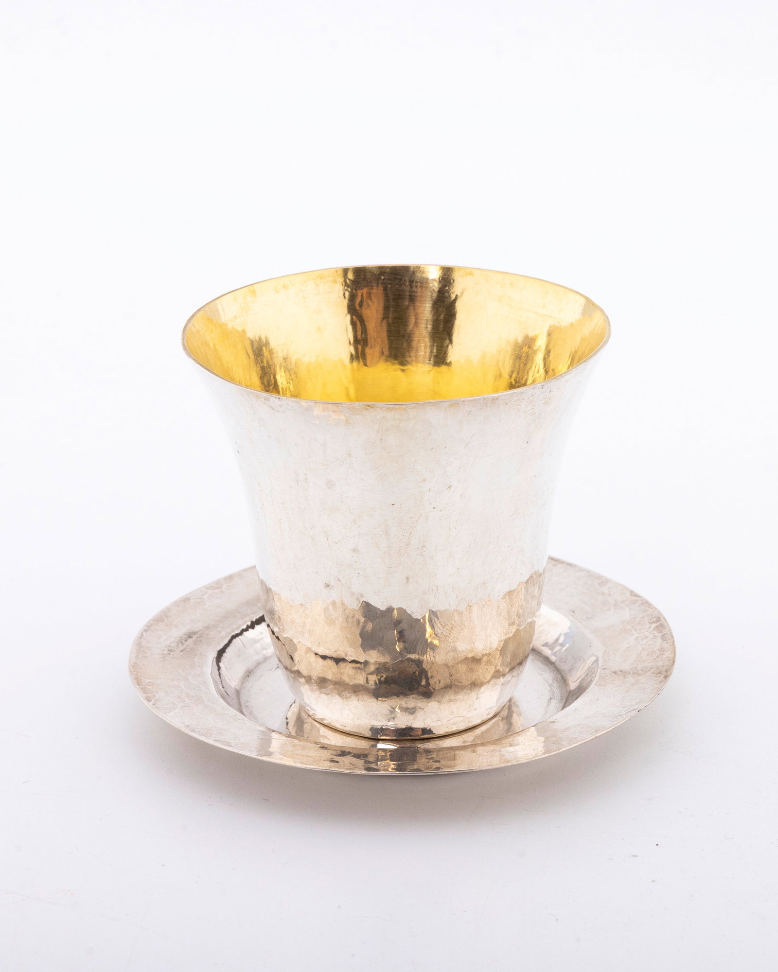 A STERLING SILVER KIDDUSH CUP AND UNDERPLATE BY DOVID COHEN. Israel, modern.: Hand wrought and hand hammered. Gilded interior. The plate is 3.7" wide and the cup is 2.9" tall and 2.8" wide. Total weight is 134.6 grams