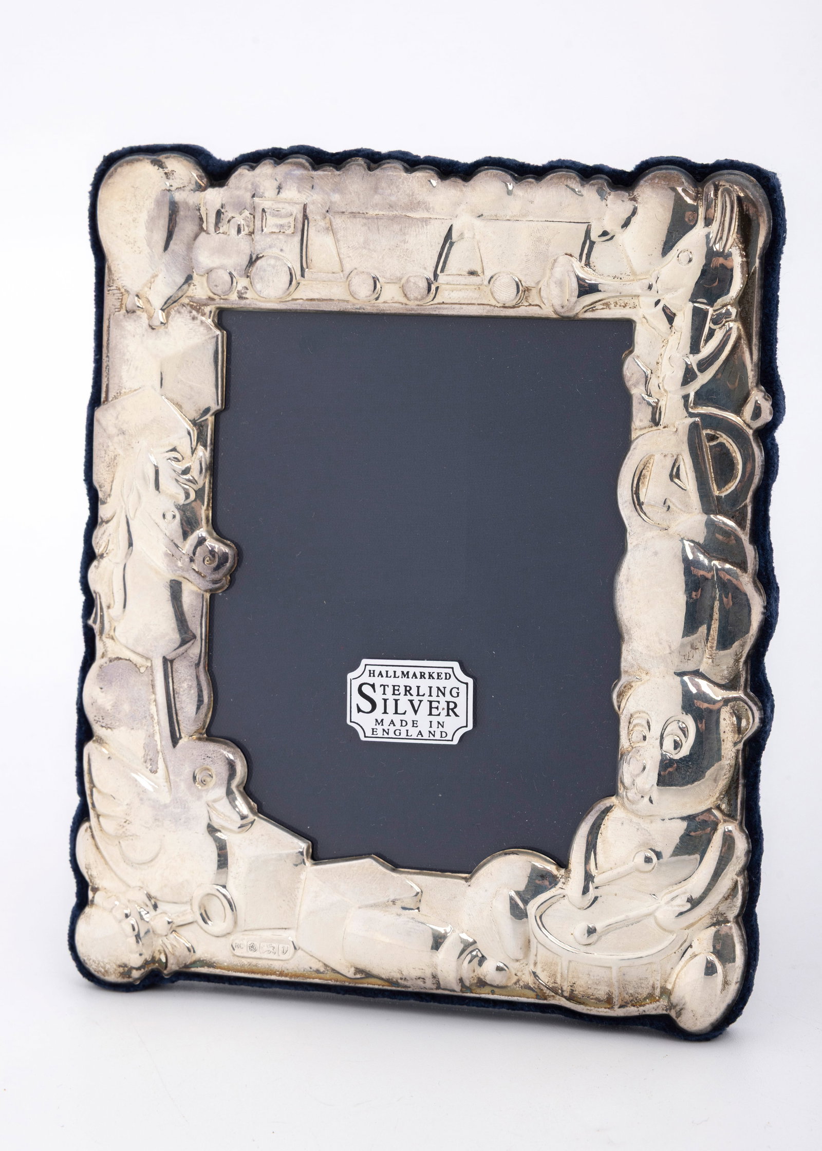 A STERLING SILVER PICTURE FRAME. London, 1995: Decorated with embossed designs of a train ,a horse a teddy bear and a duck. 4.7" x 5.5". In the original box.