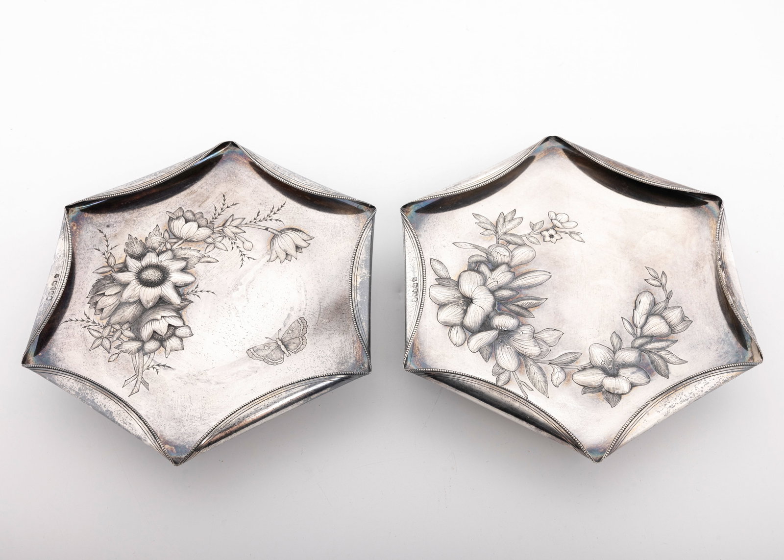 A PAIR OF STERLING SILVER VICTORIAN TAZZAS LONDON Horace Woodward Co Edgar Finley & Hugh Taylor 1885: Each on a round pedestal, embossed with floral and leaf motifs. Beased folded in rims. Retailed by Howell and James. 7.2" wide each and total weight of 836 grams.