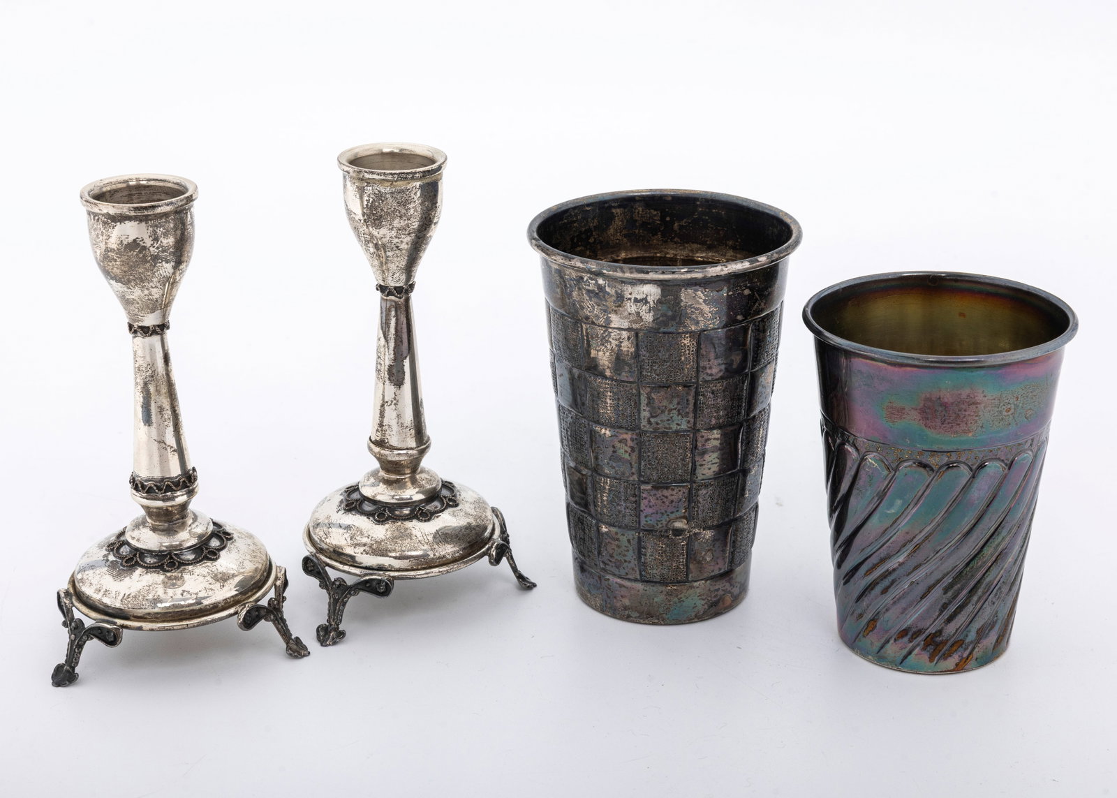 TWO STERLING SILVER KIDDUSH CUPS AND CANDLESTICKS. Israel, modern: Both cups are in modern designs Marked 925 and Sterling 4" and 3.5" respectively. Total weight 149.5 grams for the cups. The candlesticks are 5" tall and 87 grams.