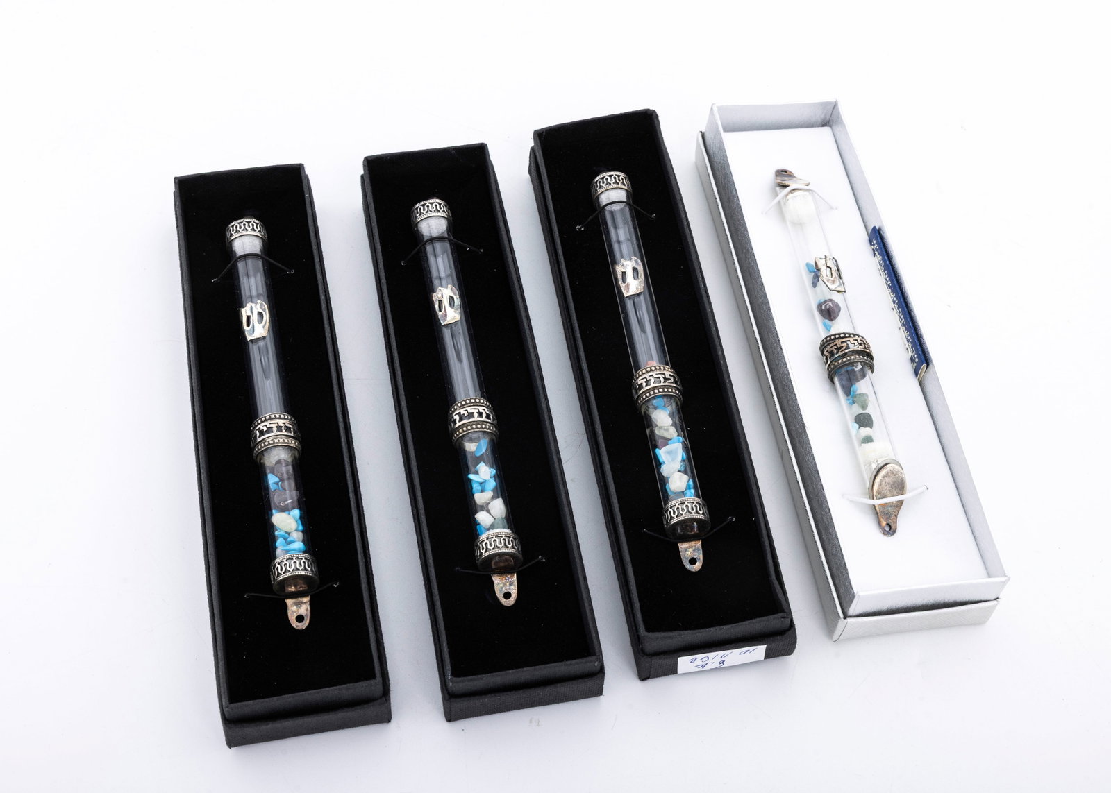 A GROUP OF FOUR STERLING SILVER AND GLASS MEZUZOT. Israel, modern.: FOUR STERLING SILVER AND GLASS MEZUZAH CASEs BY ARBIV MISHAN. Israel, modern. Hand made with polished stone inserts. 6.2” long. In the original presentation boxes