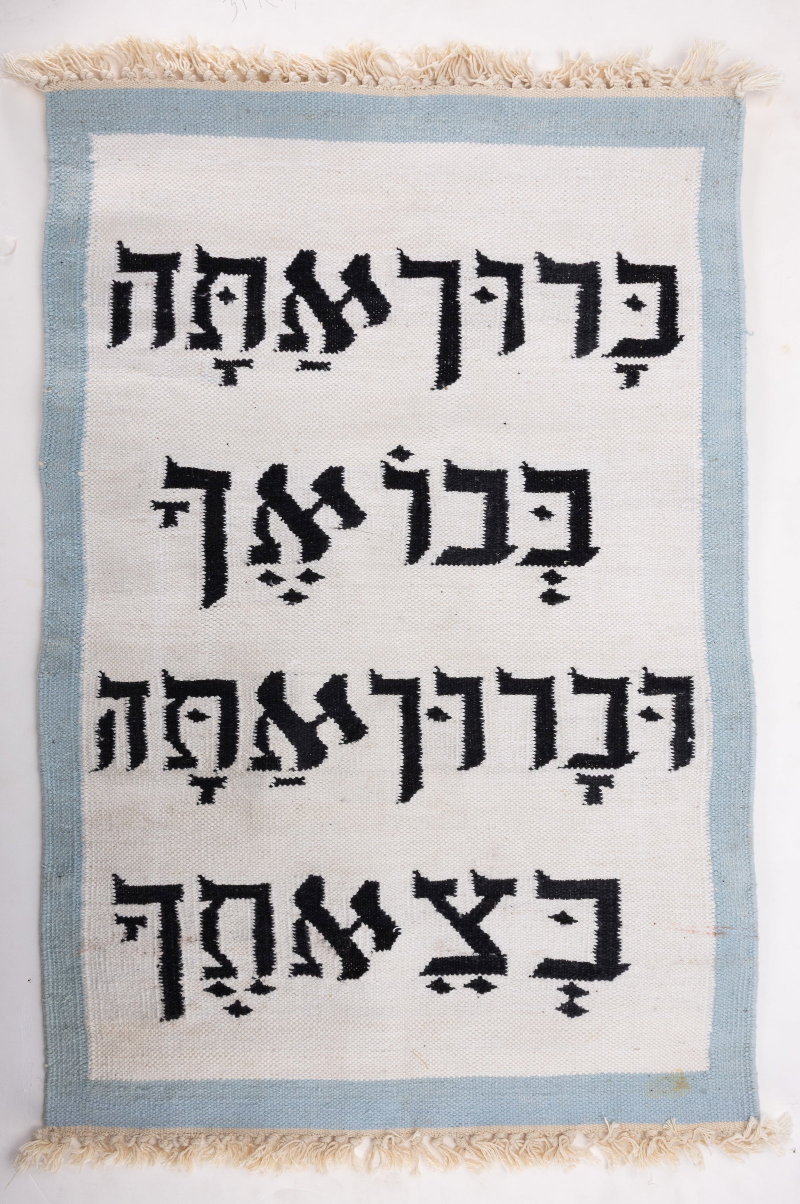 A INDIAN JEWISH RUG. c. 1980: Hand woven carpet with Hebrew blessings. Blessed are you when you enter and blessed are you when you leave. Cotton on cotton. Custom made for Jewish client possibly for a Synagogue use. 38" x 24".