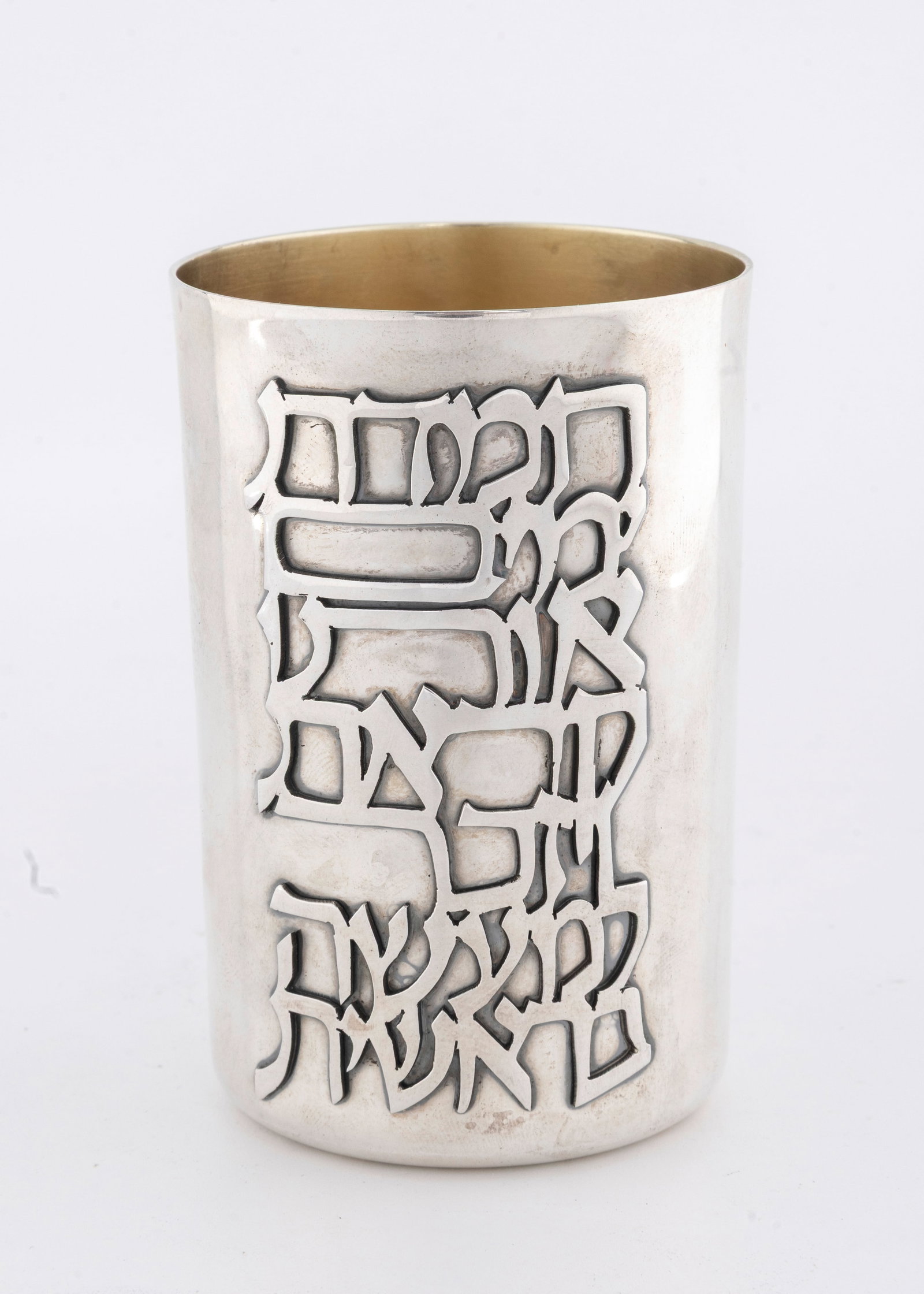 A HAND WROUGHT KIDDUSH BEAKER BY DOVID COHEN. Jerusalem, modern.: Beaker form with hand cut overlay with an excerpt from the Sabbath meal hymns. Signed. 
